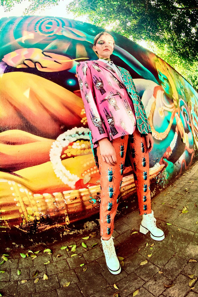 Photo of a model wearing a colorful suit in front of a vibrant mural.