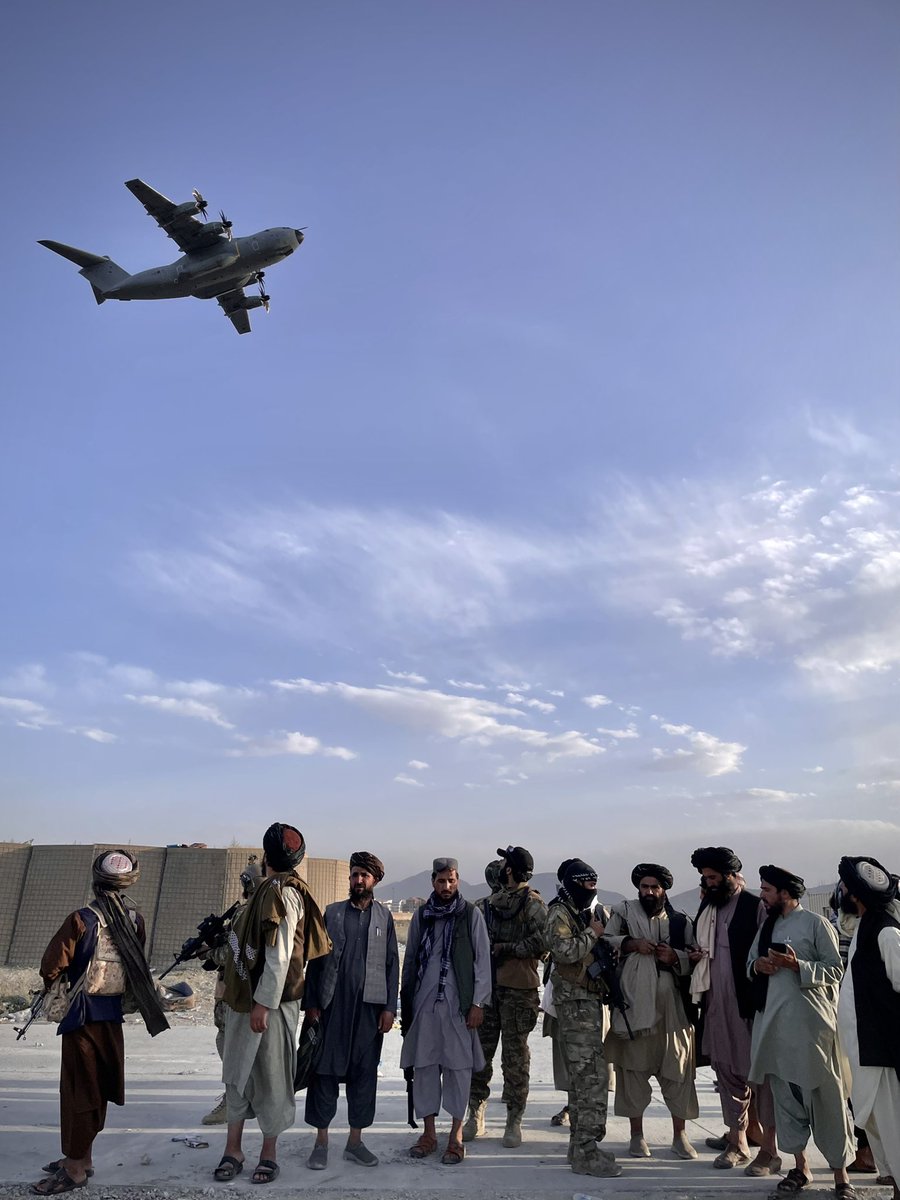 CharlotteBellis's tweet photo. Taliban fighters watch from the end of the runway at Kabul airport as a military plane takes off. Took this on my #iPhone on Saturday. @AJEnglish https://t.co/znoLKilyj5