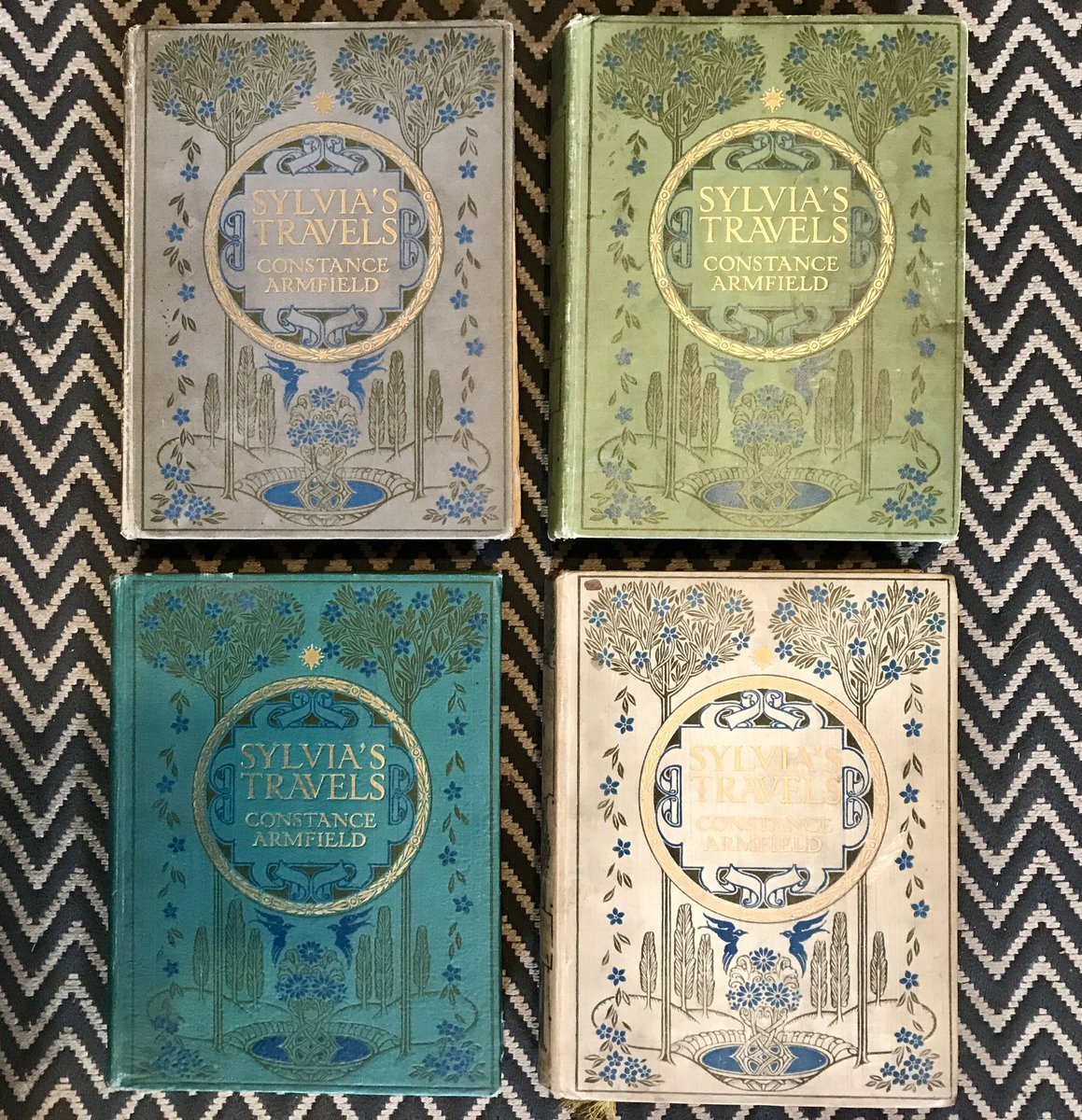 ColugoBooks's tweet photo. Well this is a mystery to me. Four apparent first editions of Sylvia’s Travels by Constance Armfield exquisitely illustrated by her brother Maxwell Armfield (1911), two different publishers, four different coloured covers… @Sotherans any ideas please? #books #bookcollecting https://t.co/qPZdF8qYAJ