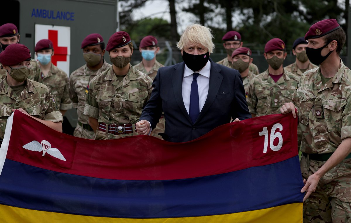 Prime Minister Boris Johnson and soldiers holding the flag of the 16 Air Assault Brigade
