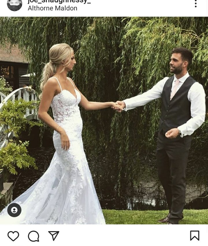 My sister and her husband at their wedding holding hands. Evie is wearing her wedding dress and they are standing in front of a small lake and a bridge.