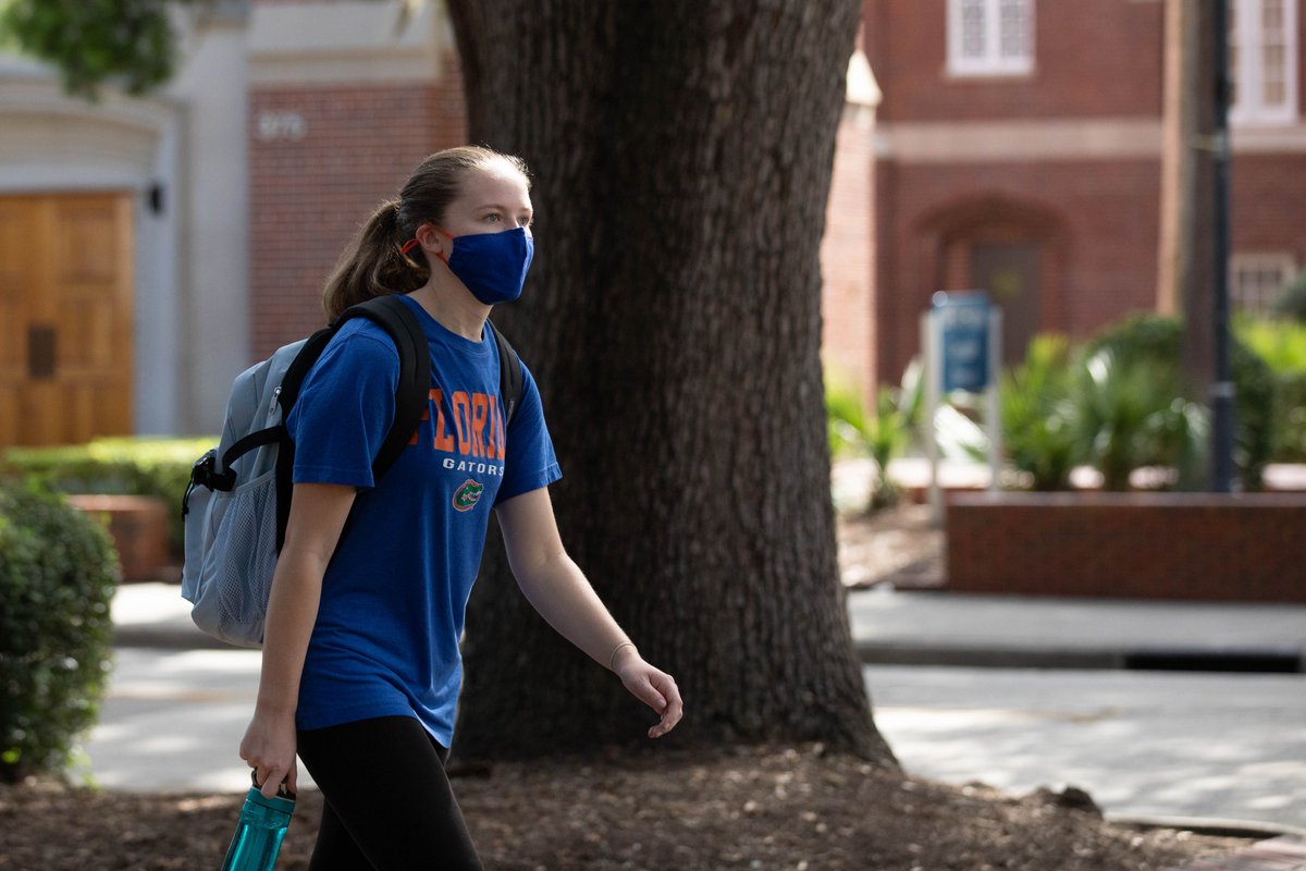 A student walks to class in a blue shirt and mask