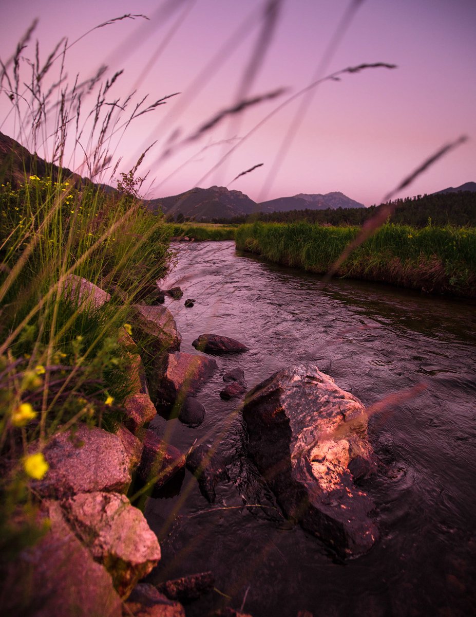 Photo of a stream with pink-hued skies above it.