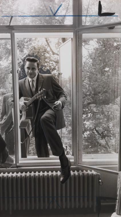 Johnny Cash climbing through a window, guitar in hand, taken in September 1959.