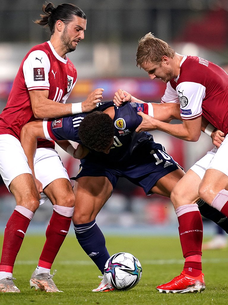 Ché Adams wrestles for possession with two Austria players.