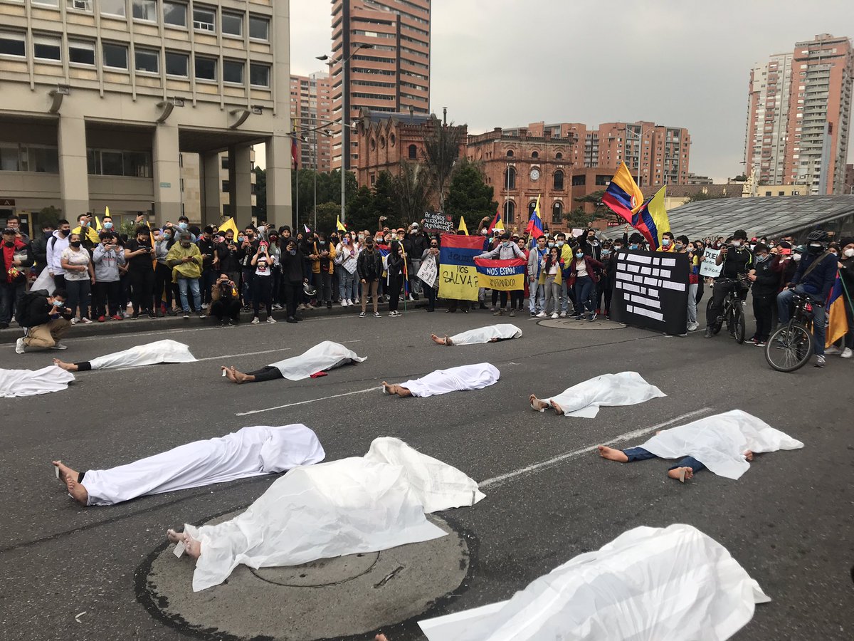 A group of demonstrators block a road in Bogota to protest against those who have lost their lives at the hand of the police during the ongoing protests in 🇨🇴. They lay on the road with white sheets over them and name tags on their toes to represent those who have died. https://t.co/f5ZLnIfqd6