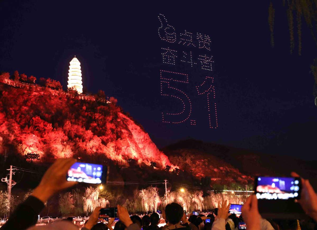 ChinaDaily's tweet photo. Some 705 unmanned aerial vehicles form "Thumbs up for those who work hard" during a high-altitude light show over Baota Mountain in Yan'an, Shaanxi province, to celebrate International Labor Day and the 100th anniversary of the founding of CPC. https://t.co/aPzR72cJLc https://t.co/mKQvJCpy0m