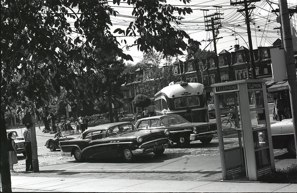  #TPBscan #26Last photo from this roll.Phone booths, streetcars, and vintage vehicles at Gerrard and Parliament. Taken from the southeast corner, looking northwest across the island parkette.I’m no car guy, but I do enjoy some of the old ‘50s/‘60s models in these pics.