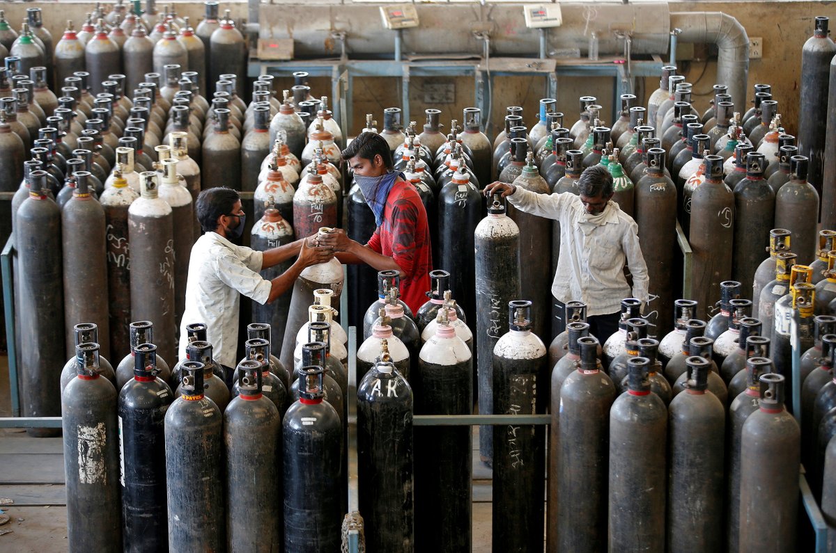 People carry oxygen cylinders after refilling them in a factory in Ahmedabad, India, on Sunday.  Amit Dave / Reuters