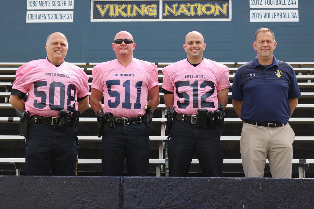 The tradition of our SROs wearing pink football jerseys continues. Former South SRO Officer Baker, along with current SROs Officers Bentley and Dagenhart, pose with Coach Miller in his last season as head football coach. @SouthIredellFB