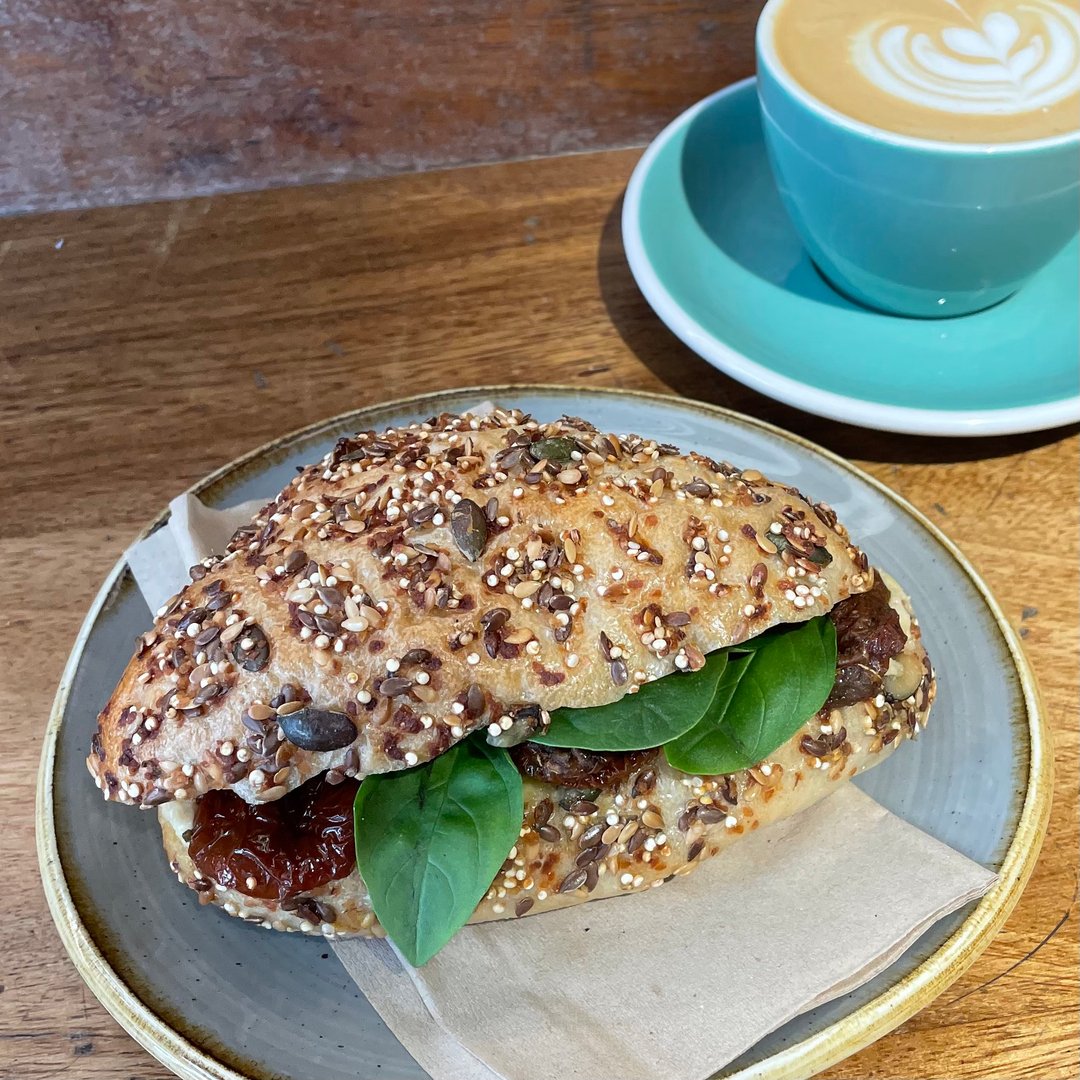 🌱 🌱 Hello to our exseedingly good vegan ciabatta, hummus, sun dried tomatoes, basil, spinach and a sprinkle of pumpkin seeds. What more could you ask for? 
•
•
•
#vegan #veganlunch #lunchtime #ciabatta #seeds #friday <a href="/thebreadfactory/">Bradley</a> #latteart #coffee #specialtycoffee
