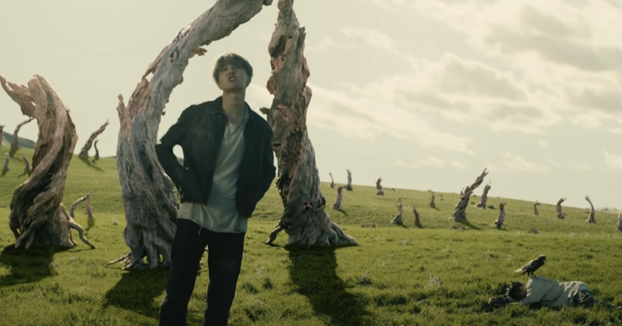 We're now in a forest of dead and twisted mythical-looking trees, with a fallen Jungkook on the ground. This is the Garden of Eden, now destroyed by the flood. Hoseok, in his modern clothes, represents a person from the future, walking in the place where Heaven was once on Earth.
