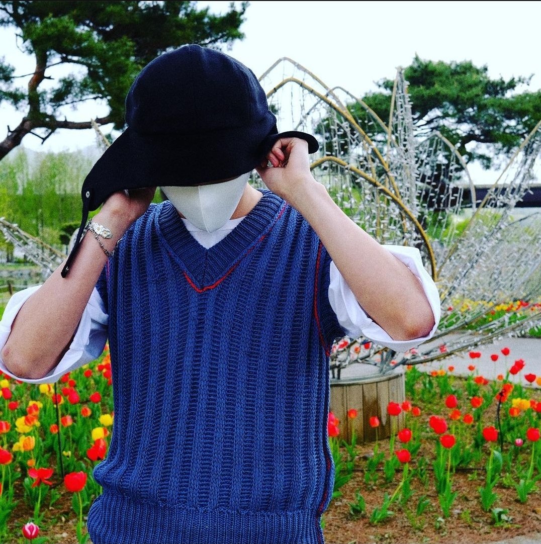 Adjusting hat with face downturned