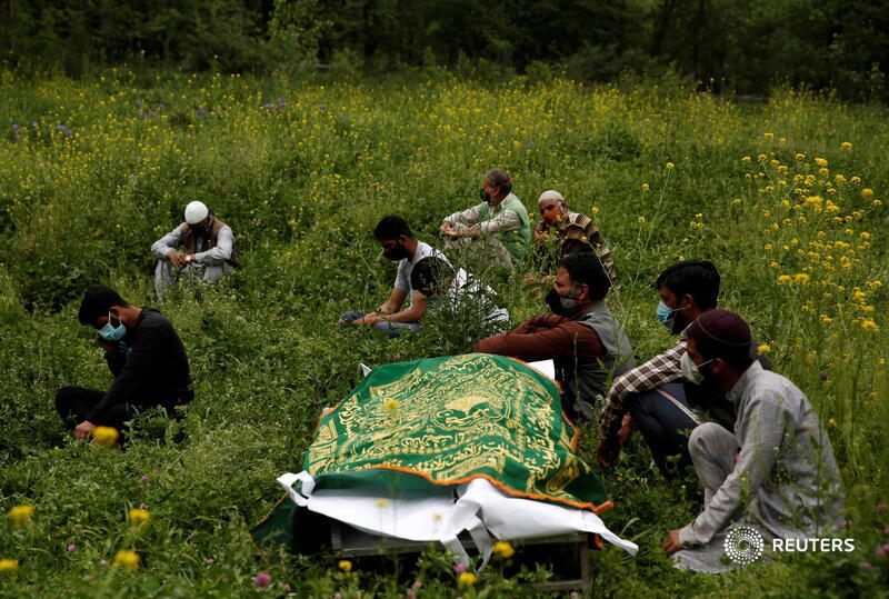 Relatives sit next to the body of a man who died of the coronavirus, as they wait for a grave to be prepared for his burial on the outskirts of Srinagar. More photos of the day: https://t.co/XN6Y89c7EY 📷 @900Danishismail https://t.co/8IW8Icait3