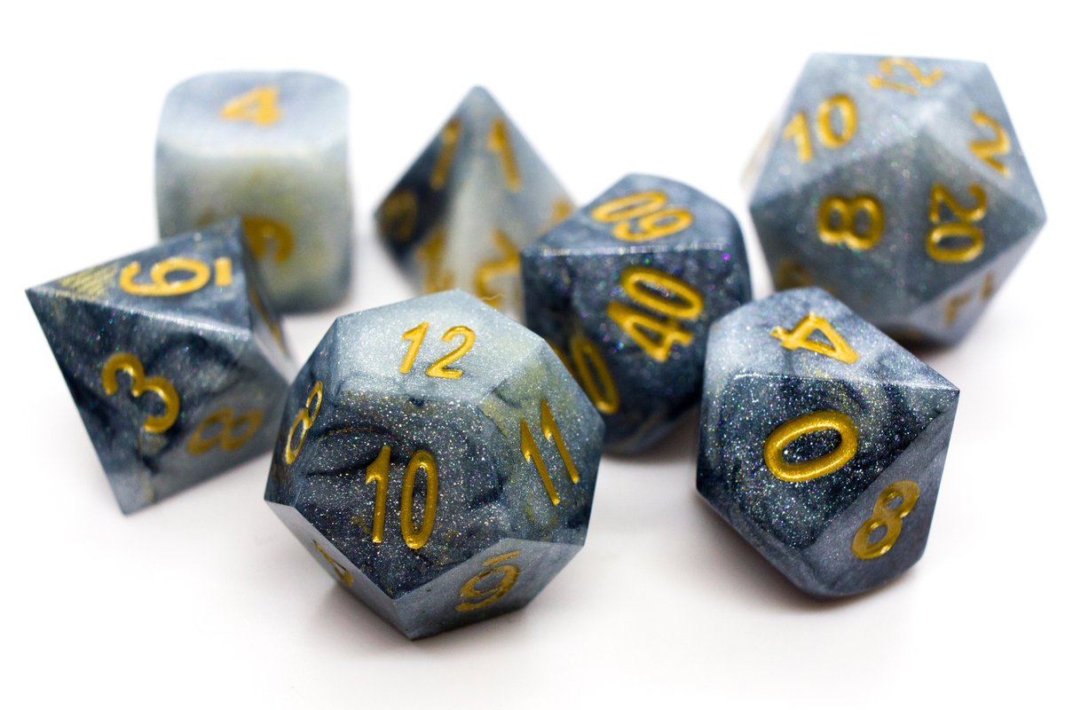 Handmade resin dice in different shades of grey and subtle golden spots on some dice, gold ink for the numbers, very minor flaws on some of the facets that face the lid --> 60 Euro excluding shipping.