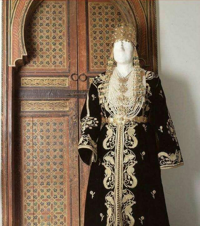 Le caftan 𝑵𝒕𝒂𝒂Caftan de velours de soie souvent noir ou vert foncé, brodé au fil d'or (sqalli)Ce caftan tire son nom de la broderie (tarz) Ntaâ, caractérisée par l'apparition de motifs floraux et/ou de paonDe nos jours, la robe est portée par la mariée le jour duhenné