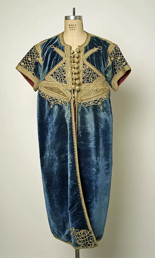 Le caftan d'OujdaCaftan aux manches courtes en velours de soie brodé en soutaches, galons et fils d'or. Il comporte deux motifs ovoïdes de part et d'autre. Il était spécialement porté lors de cérémonie de mariage