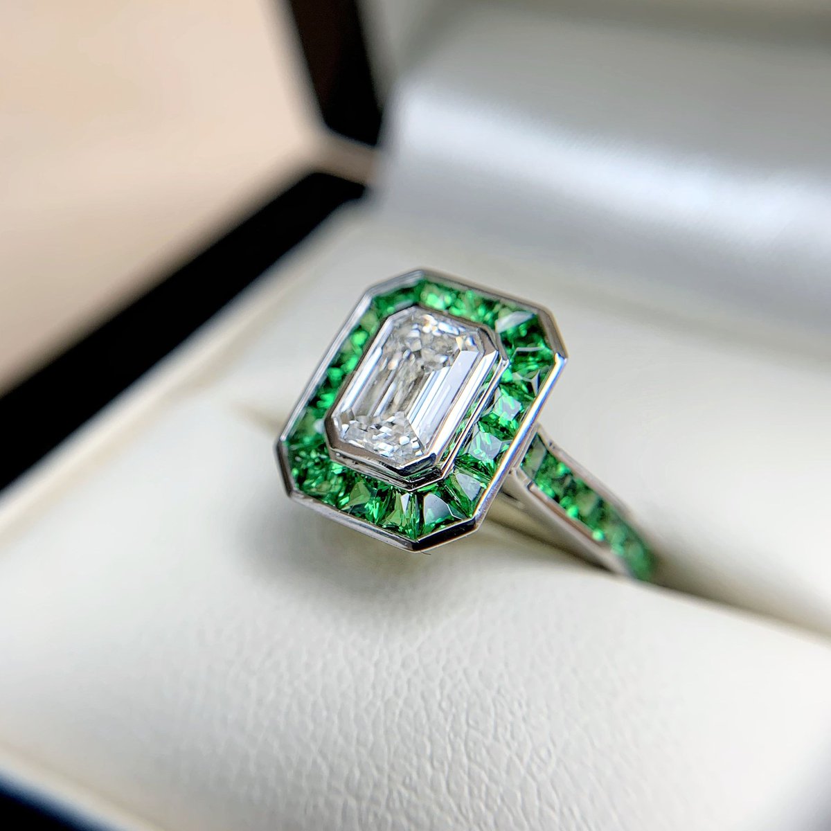 The roaring 20's doesn't get much more glamorous than this. A homage to art deco featuring an emerald cut diamond surrounded by tsavorite garnets. #engagementring #finejewellery #roaring20s #artdeco
