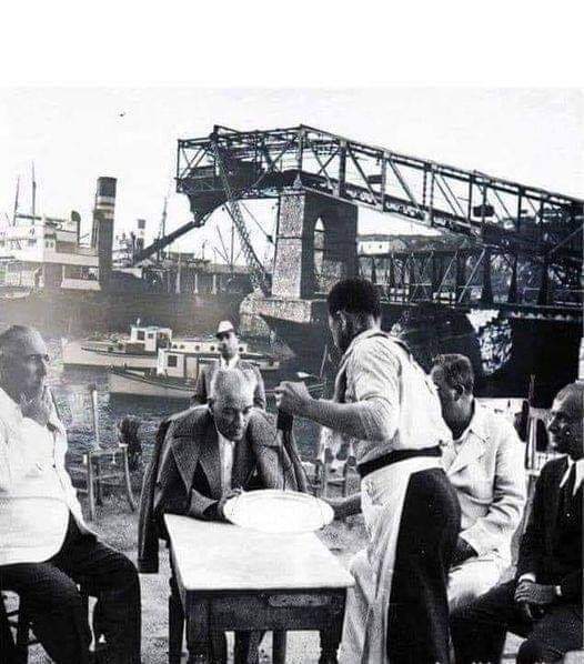 Şu fotoğrafın güzelliğine bakar mısınız?
Mekân belli değil ama büyük ihtimalle bir liman kahvesi...
Paltosu omzunda, çevresinde ne el pençe divan duran var, ne de koruma ordusu!..
O, kahvesini bitirmiş, yanındakilerle sohbet ediyor...
Büyük, çok büyüksün Atatürk...