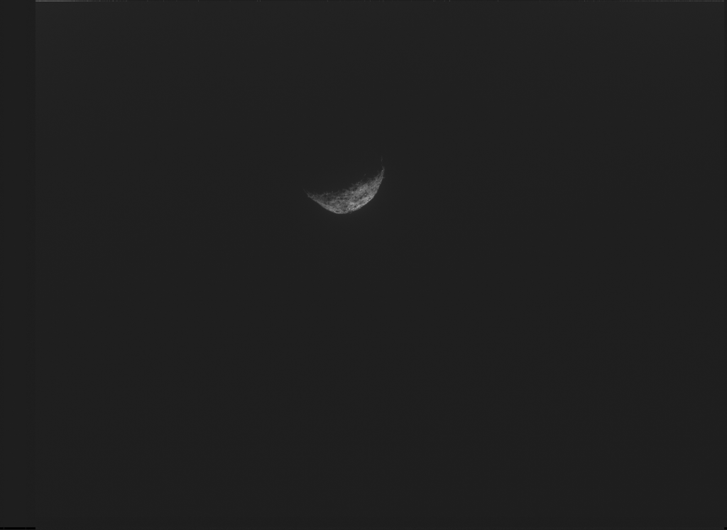 Asteroid Bennu seen in distance with one side reflecting light