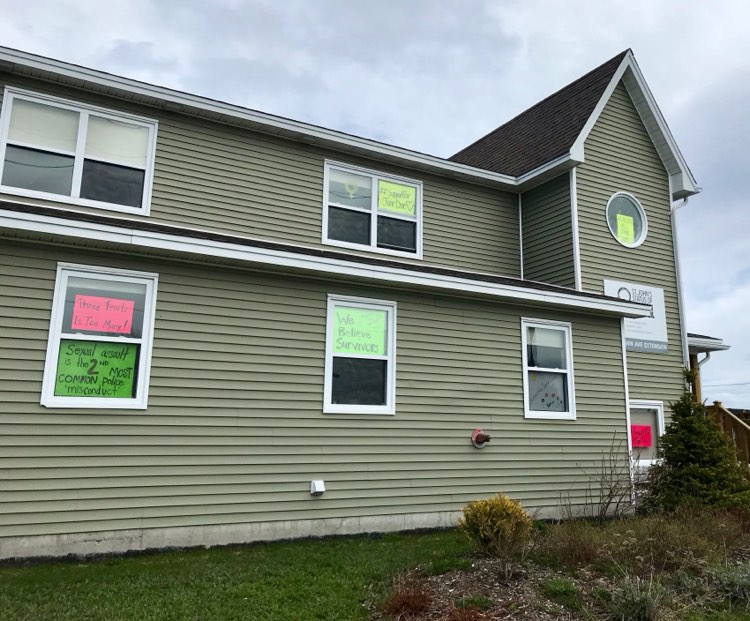 SJSWCouncil's tweet photo. We believe her. Three trials is too many. #SupportForJaneDoe ID: photo of the St. John's Women's Centre, a green two-storey building, where many windows are filled with hand written signs in support of Jane Doe. https://t.co/00mT0ub0sn