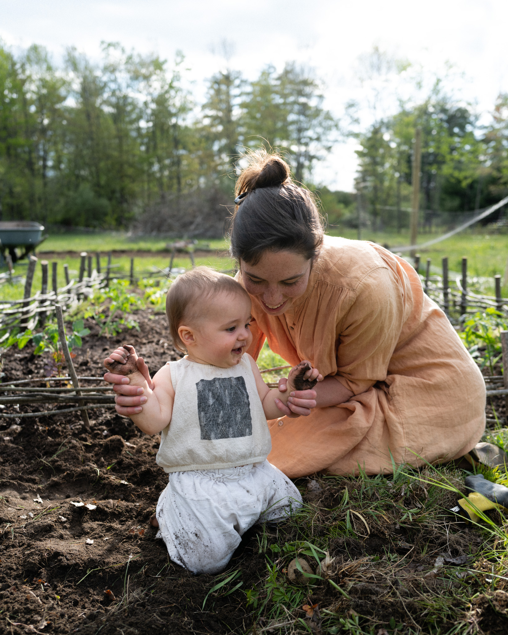 Simi and their baby playing in the black earth of their vegetable garden.