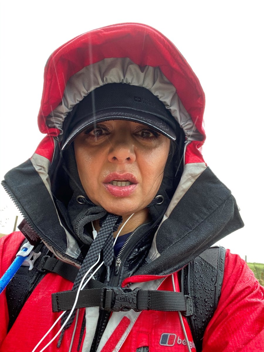 A runner with their hood up and covered in rain.