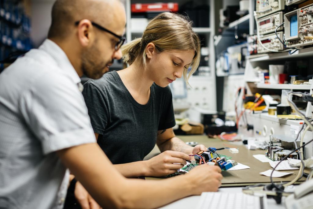 Man and woman working together on circuit board 