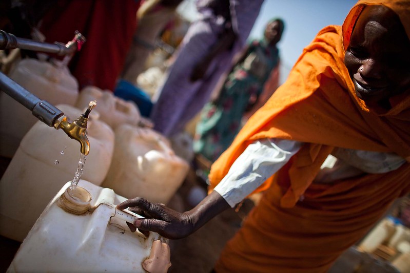A woman filling a water jug at a public tap.