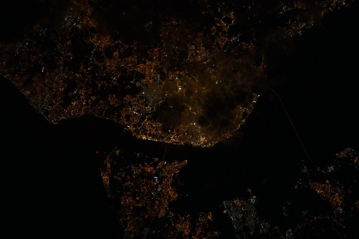 Thom_astro's tweet photo. Lisbonne ! De nuit, la ville est facile à reconnaître grâce à ses immenses ponts et à la forme de l'embouchure du Tage sur l'Océan Atlantique. Quelques nuages voilent la partie la plus lumineuse de la ville ☁️😕 #MissionAlpha #CitiesAtNight https://t.co/KD7Lz7UmBh