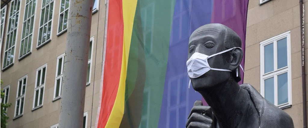 Albertus-Magnus-Statue vor dem Hauptgebäude der Uni Köln mit Mund-Nasenschutz und vor Regenbogenflagge