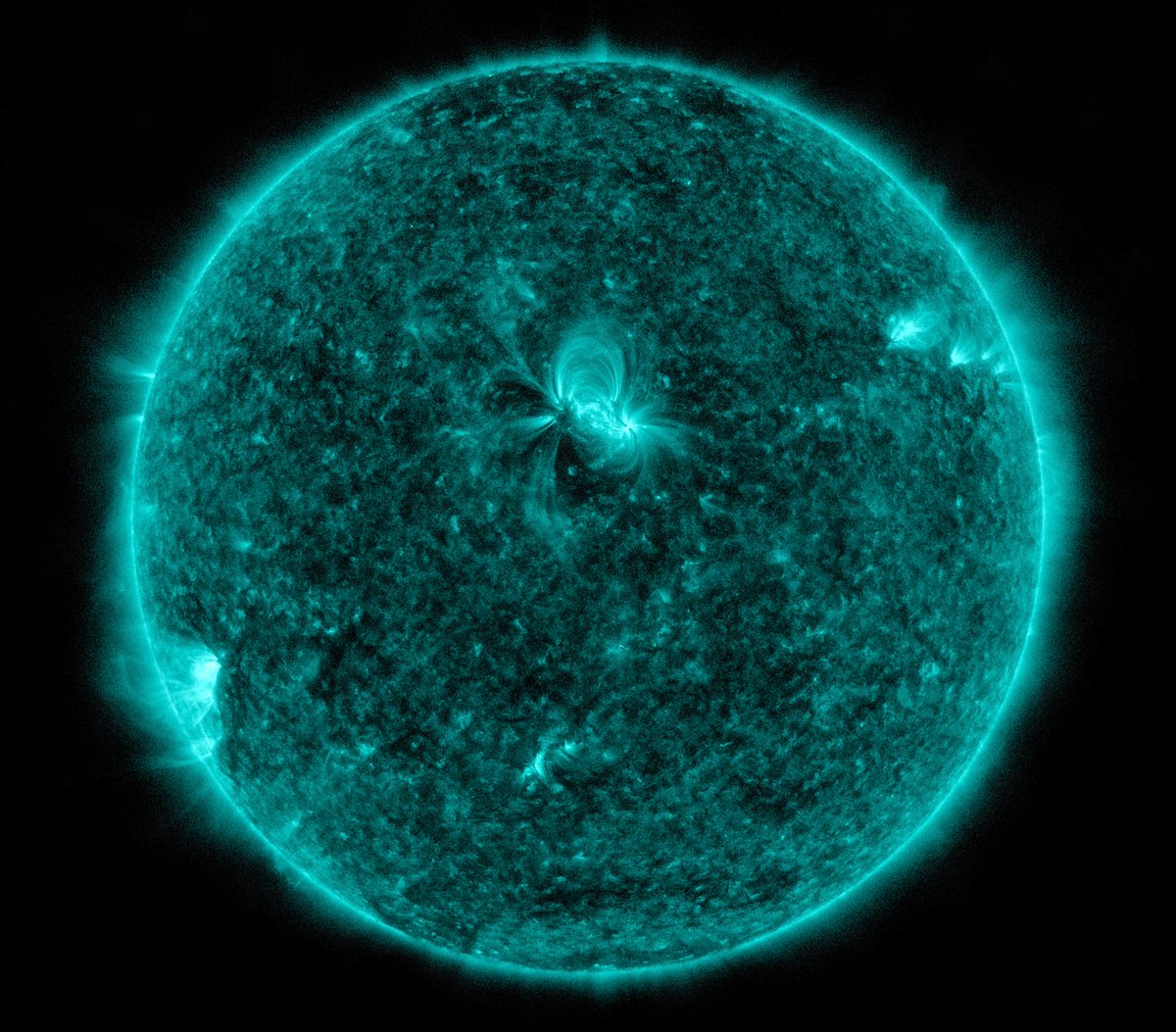 Die erdzugewandte Seite der Sonne in kalter türkisgrüner Farbe. In der Mitte und auch links am Rand und weniger ausgeprägt rechts oben helle Bereiche, in denen sich Eruptionen ereignen. Auffällig sind insbesondere in dem mittigen Bereich schleifenförmige Strukturen - ausgelöst durch Magnetfeldlinien, die von der Oberfläche ins All und zurück führen.