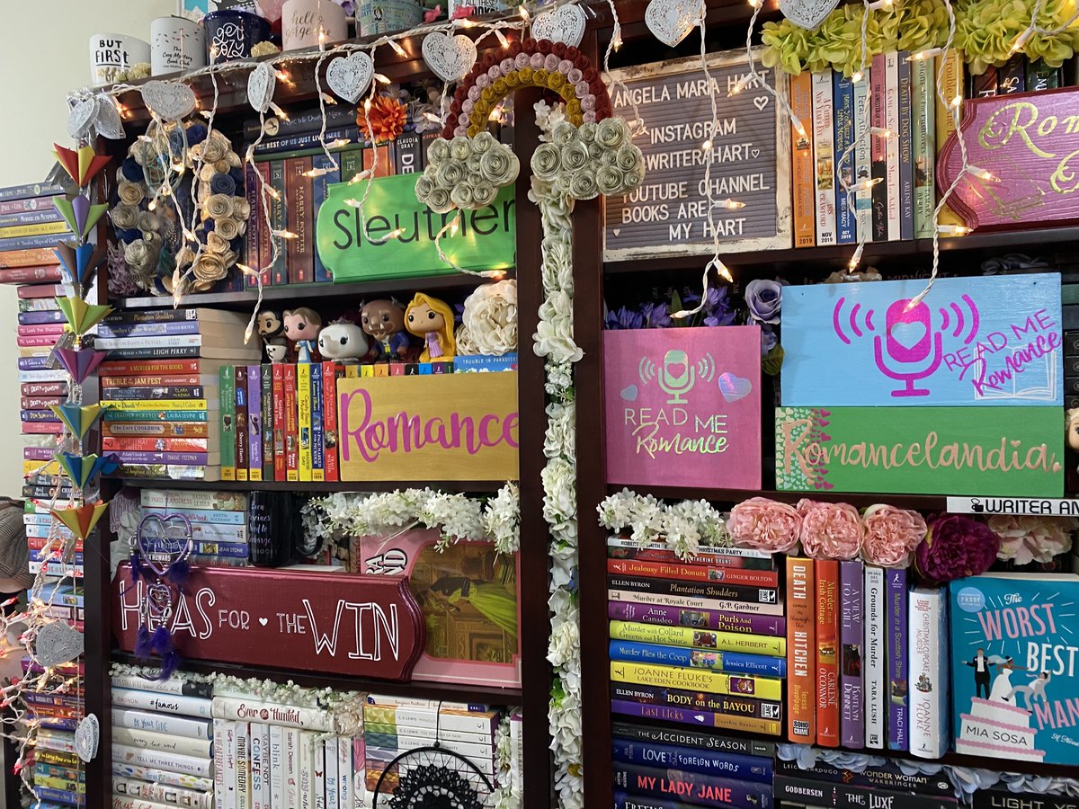 writerahart's tweet image. In the comments, I saw that there were a few posts about my bookcases. Thank you for the complements!
I did it up special for the #pcaaca21 romance crew - moving some of the signs from other bookcases and places of honor throughout the apartment to one location.