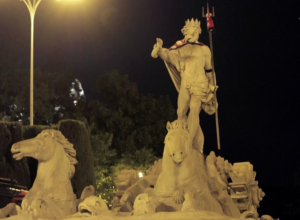 Atleti's tweet photo. 🇦🇹🔱 ¡@Koke6 cumplió con la tradición de colocar a Neptuno una bufanda y una bandera rojiblancas tras conseguir un título!

Además, rindió tributo al joven atlético fallecido anoche colocando un brazalete negro.

#OtraFormaDeEntenderLaVida https://t.co/2AsssnrT3x