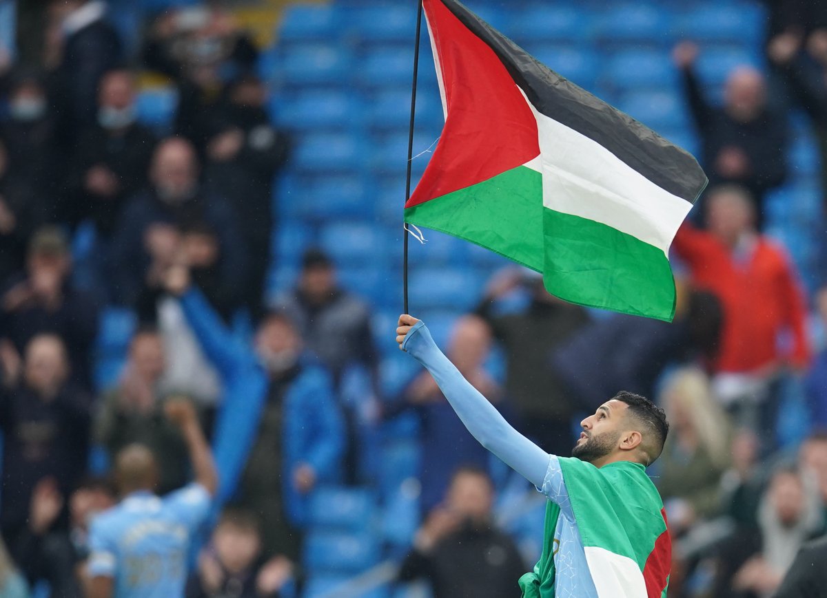 الدولي الجزائري رياض محرز لاعب مانشستر سيتي يرفع علم فلسطين وسط الملعب احتفالًا بتتويج فريقه بلقب الدوري الإنجليزي