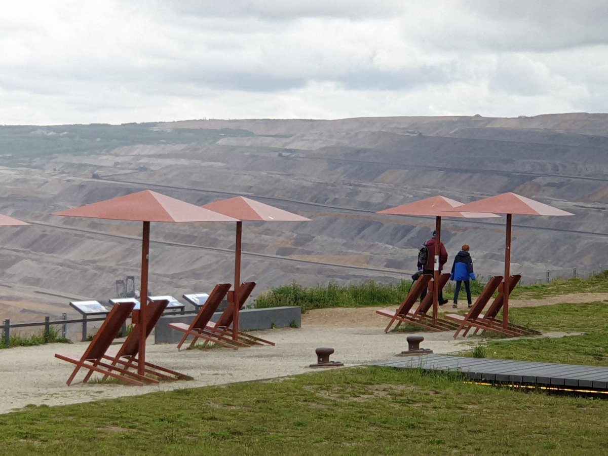 Liegestühle und Sonnenschirme vor der Abbruchkante Braunkohletagebau