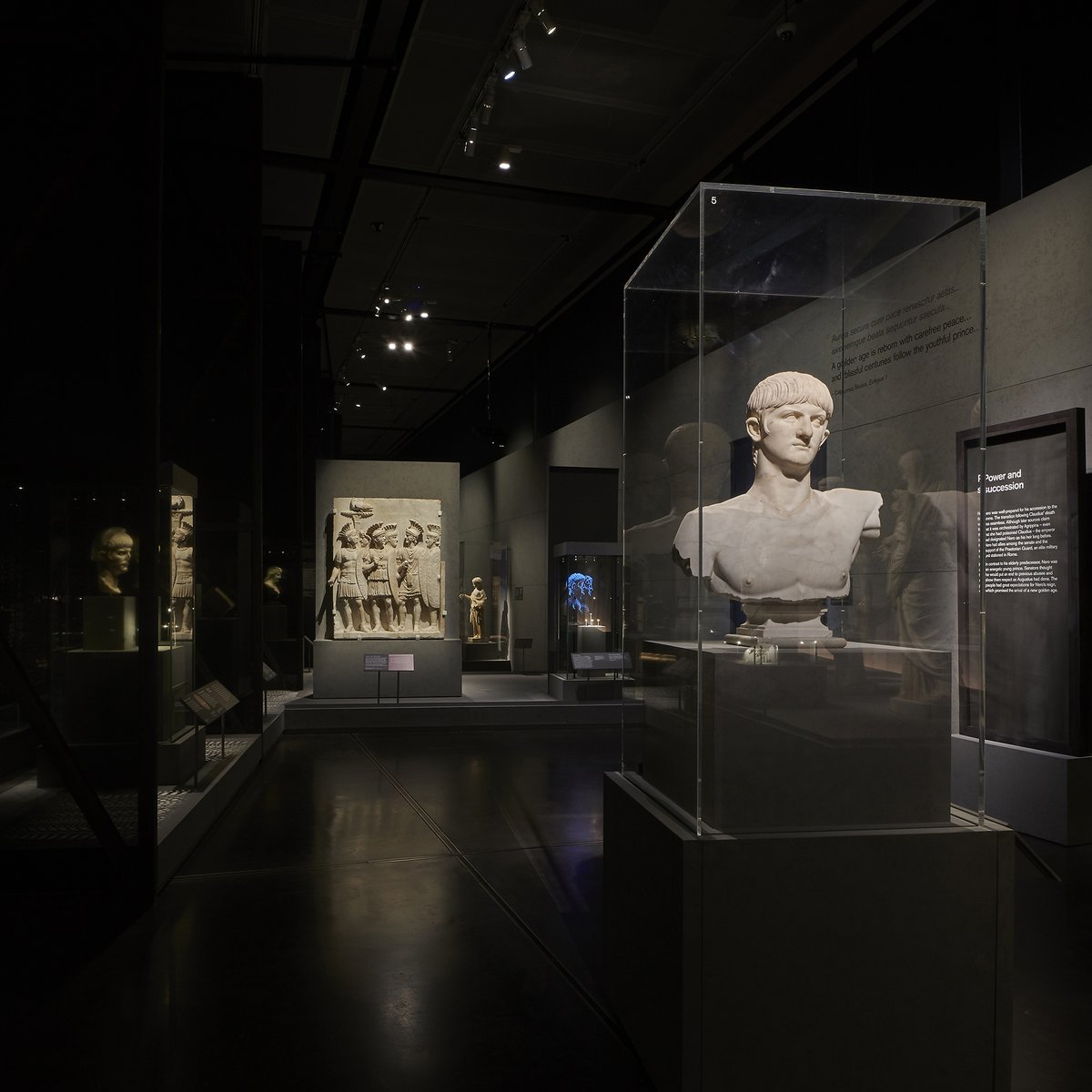 Inside the exhibition - a marble bust of Nero is in the foreground, and a stone relief showing the praetorian guard is behind it. 