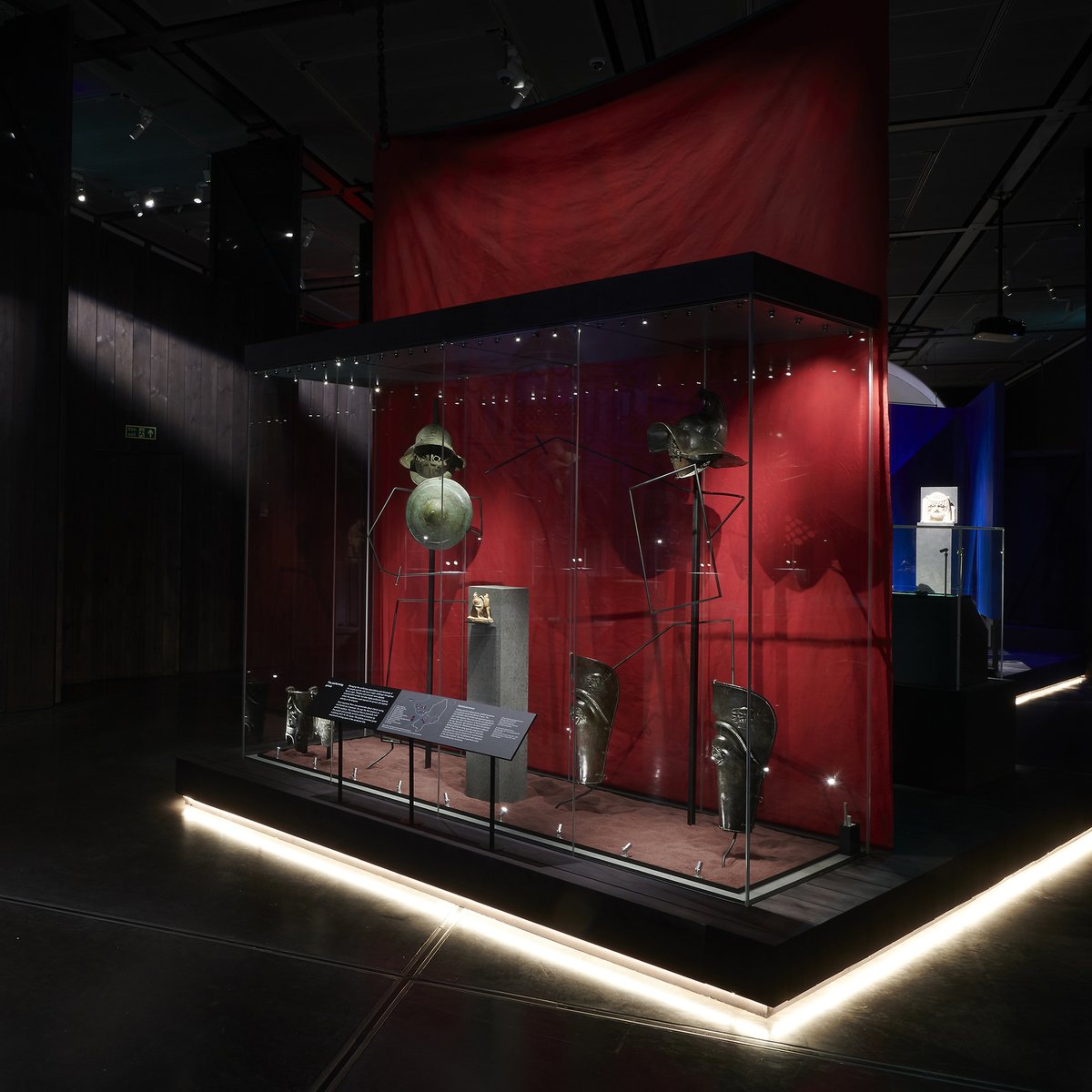 Inside the exhibition - a red case with two gladiators fighting, wearing ancient roman armour. 