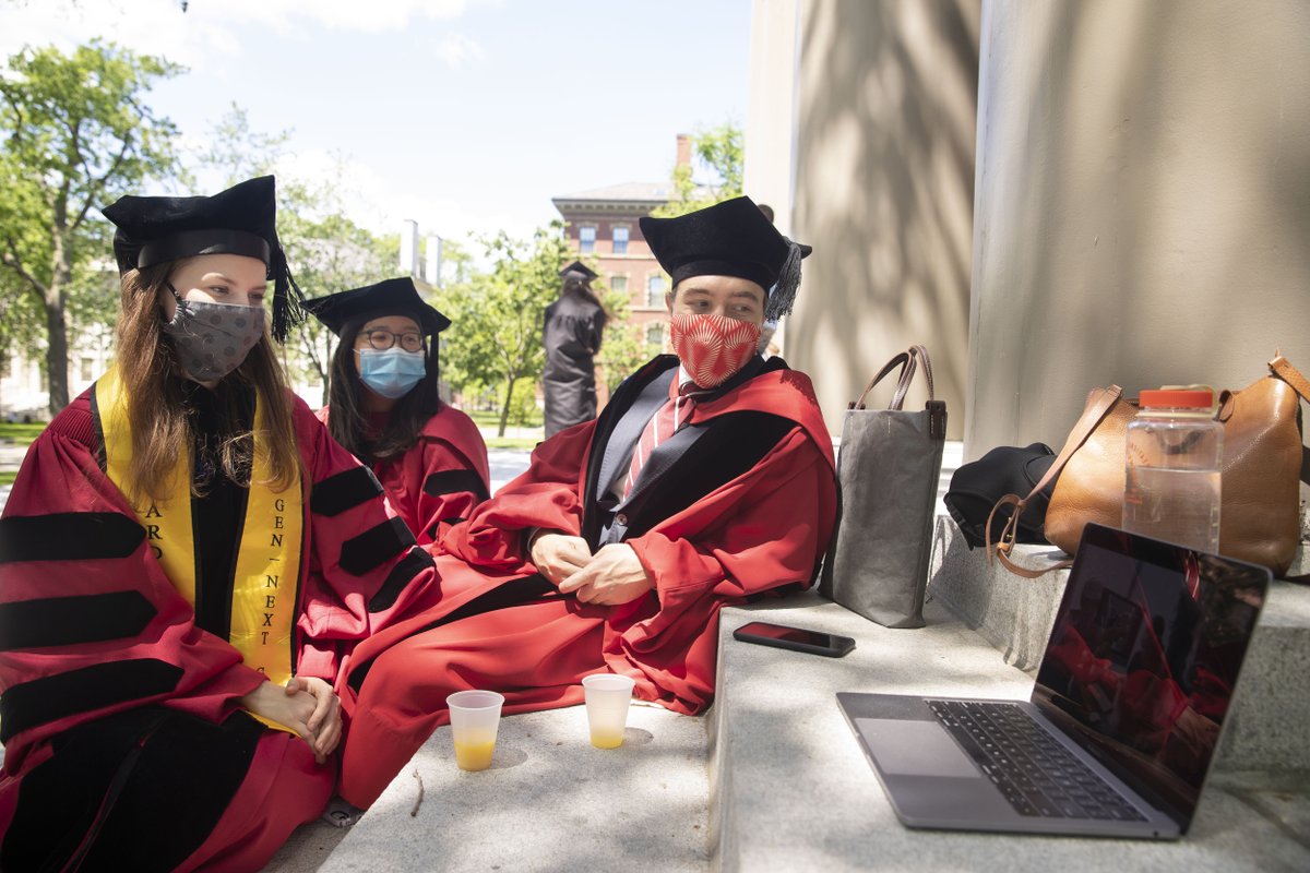 Three graduates watch the ceremony on a laptop