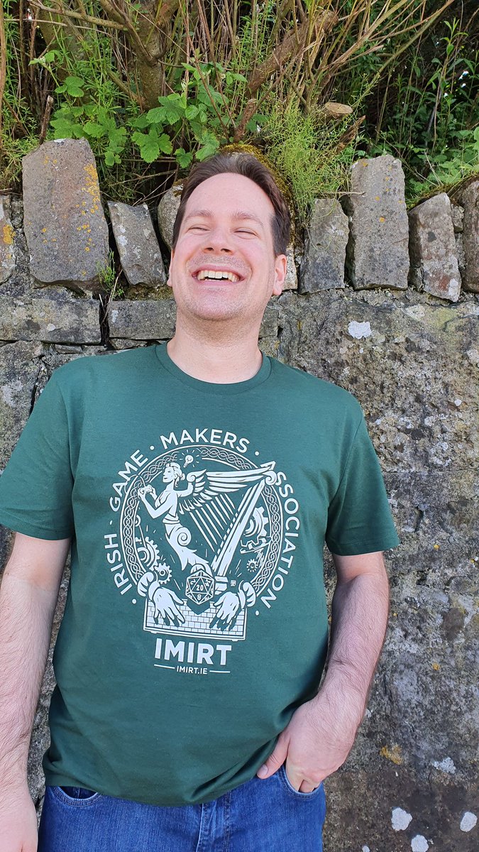 Me, smiling, with a haircut after almost a year, next to a brick wall, wearing a green t-shirt with the Imirt logo.