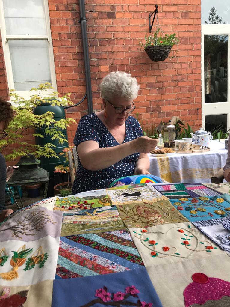 curlykath's tweet photo. A lovely morning with my community crafting group. We got together to hand sew the binding on our lockdown quilt. After working on our own since January and only meeting via zoom it was so convivial to sew together once more. @StitchingTgthr #communitycraft https://t.co/3tqzFGsKKg
