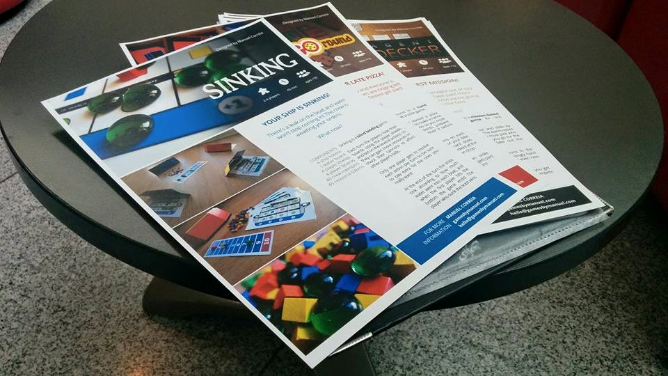 Sellsheets on a round black table, for the games for Sinking, Pizza Go Round and Agent Decker.