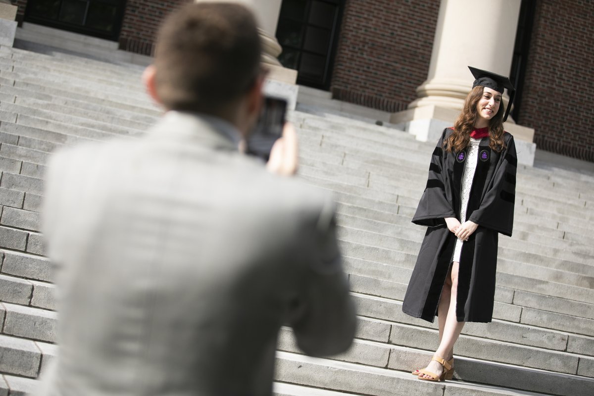 A man takes a photo of a graduate on the steps of Widener Library 