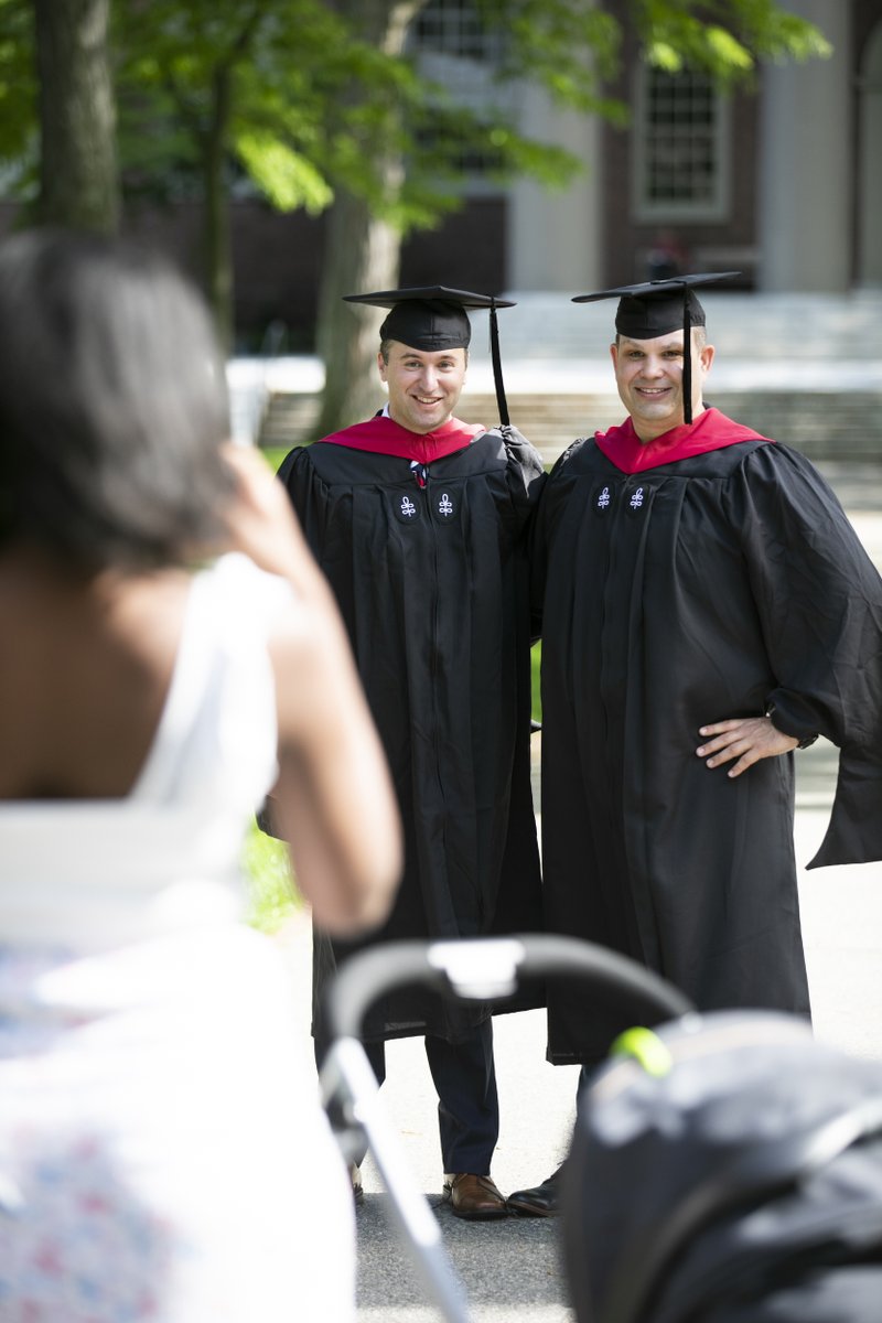 A woman takes a photo of two graduates