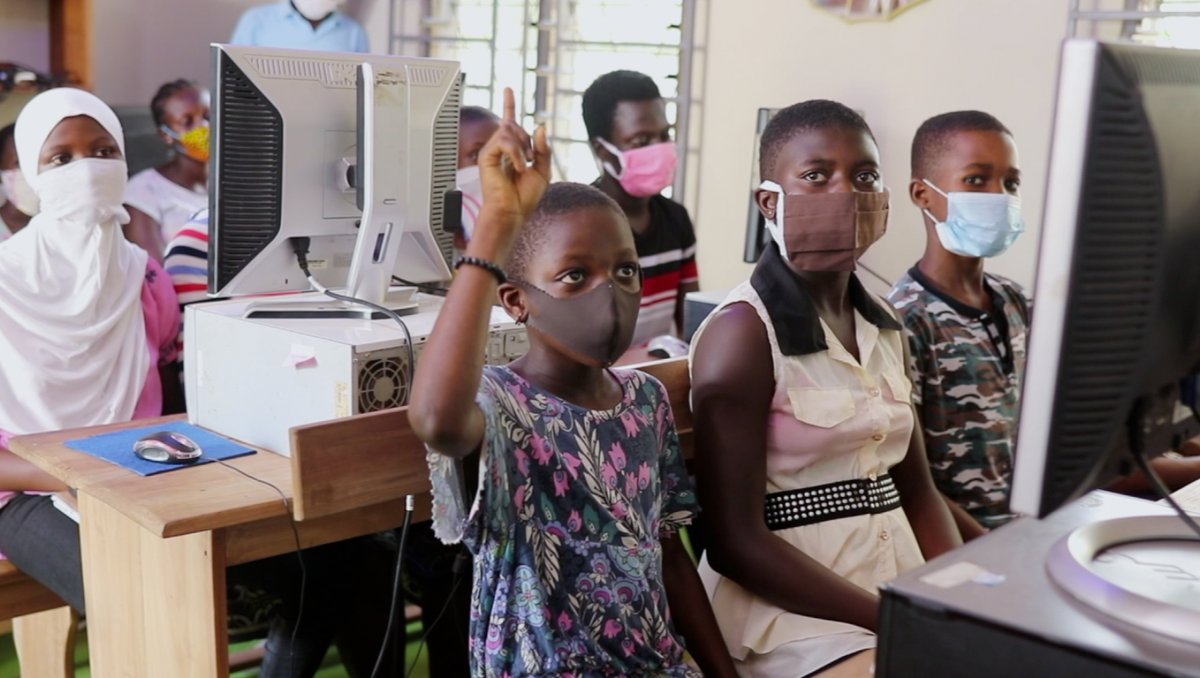 photo of school girls with face masks sat in front of their desktops at class in Ghana