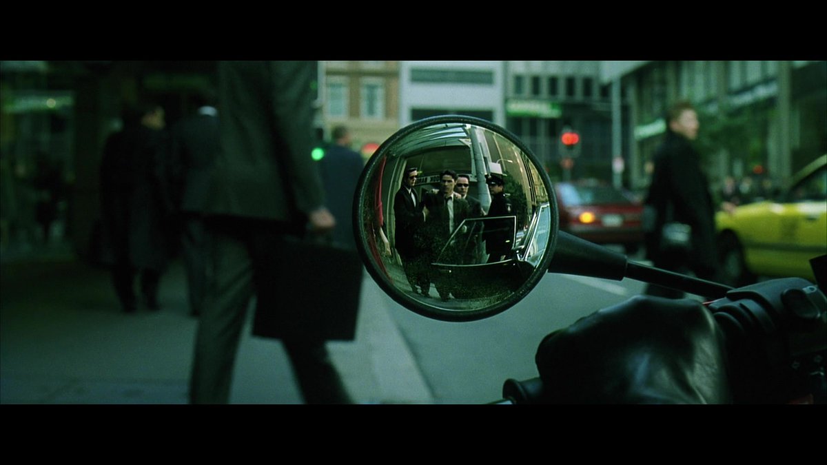 16:47- Our first mirror shot. Reflections are very important in this movie, they’ll pop up often. But this reflected image shows the world all warped. What’s Neo looking at? A WOMAN in RED. The truth is there, but distorted, and he can’t accurately see it.
