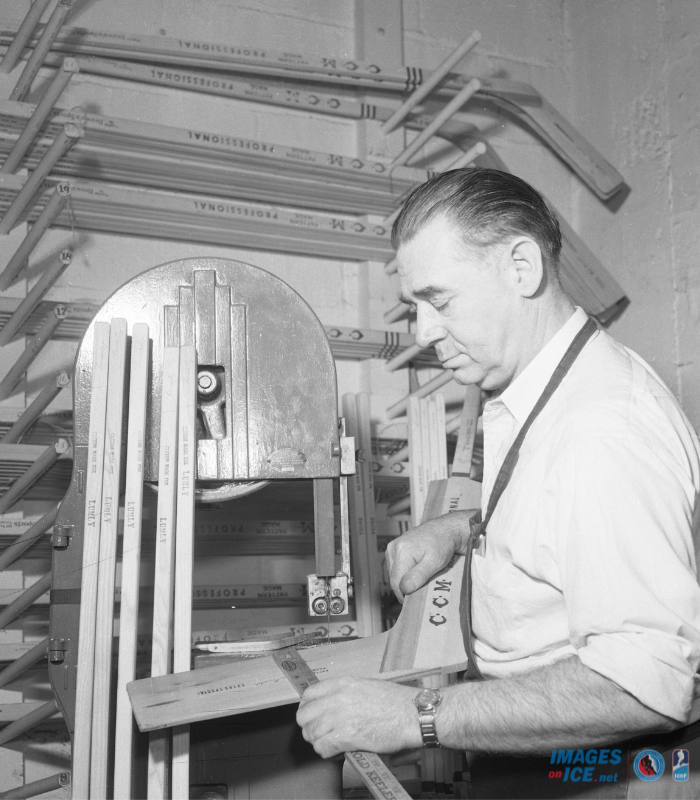 Equipment manager Tommy Naylor sands down a CCM wooden goalie stick when he worked for the Toronto Maple Leafs. Many wooden sticks hang on the wall behind him. Photo by Michael Sr Burns / HHOF-IIHF Images
