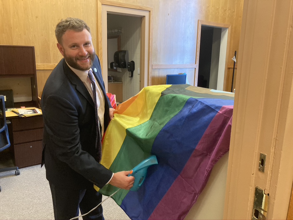 An image of State Senator Julian Cyr ironing the inclusive pride flag