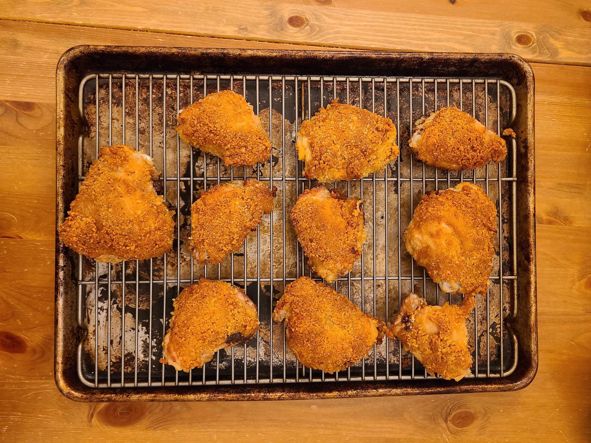 Ten fried chicken thighs, crispy and golden, sit on a wire rack