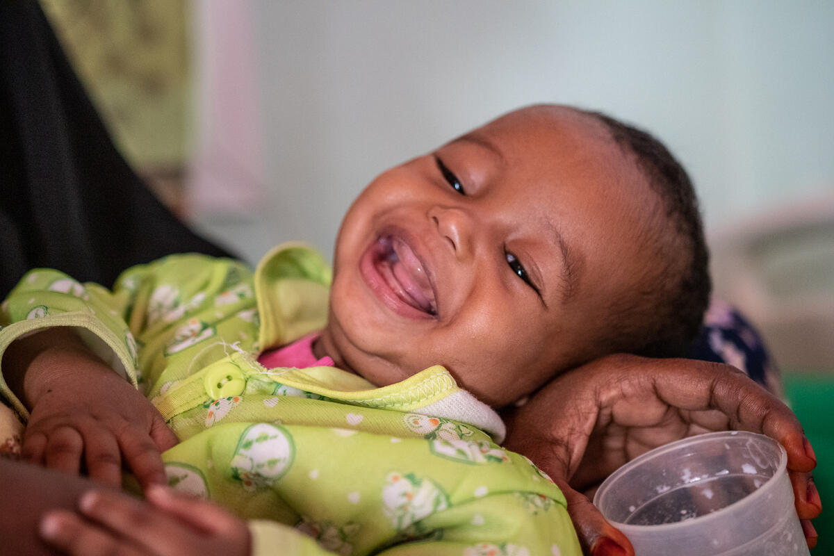 7-month-old Mohamed* laughing in his mother's arms
